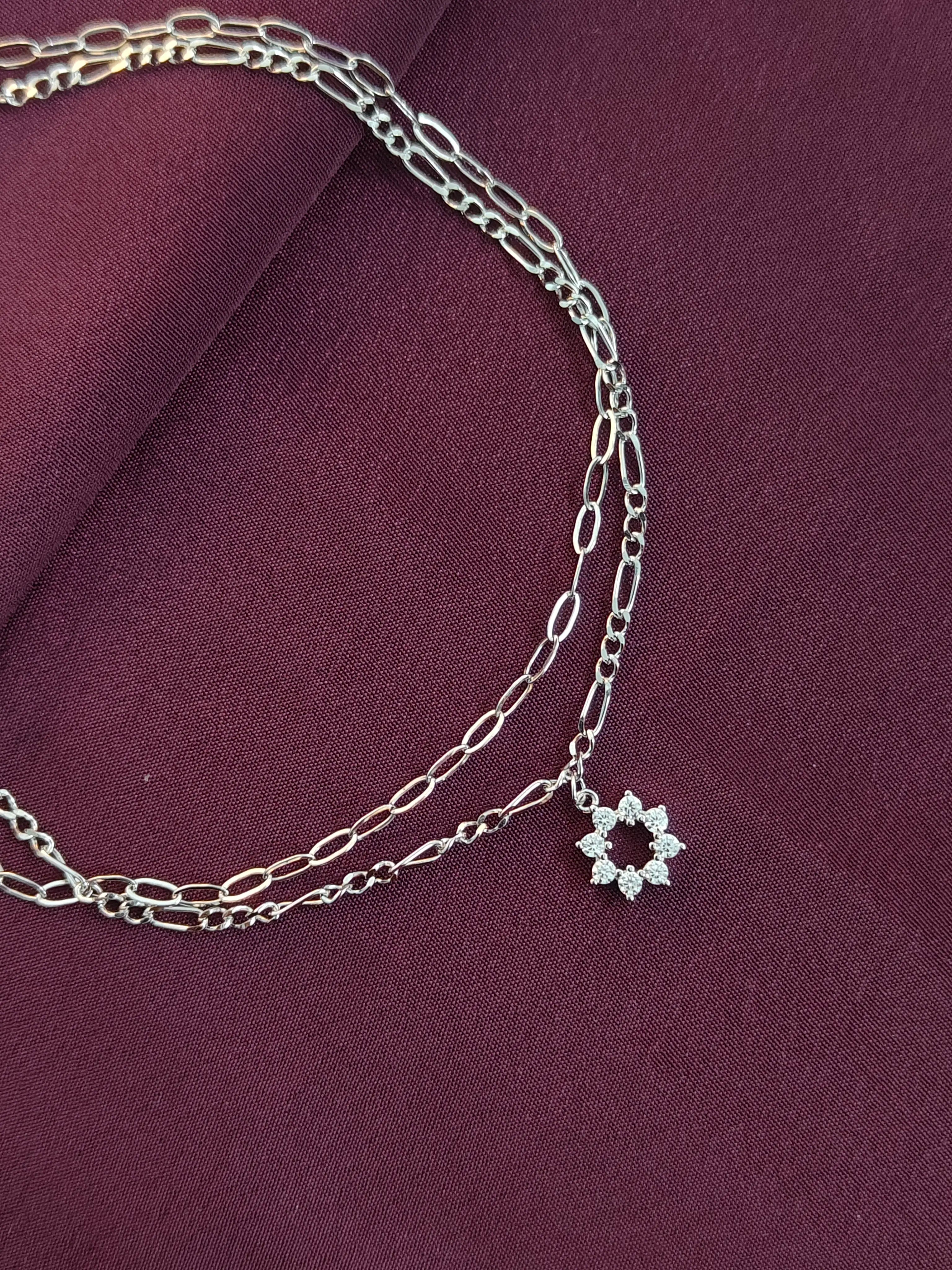 Silver chain necklace with a star-shaped pendant on a purple fabric background